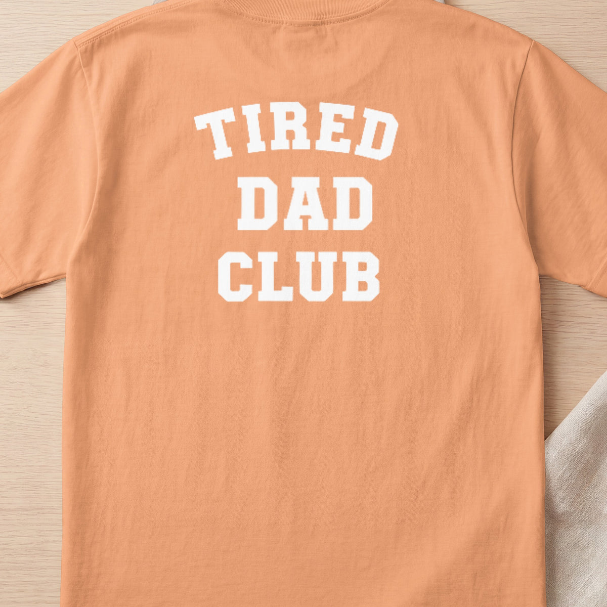 Orange t-shirt with "TIRED DAD CLUB" printed in white block letters.