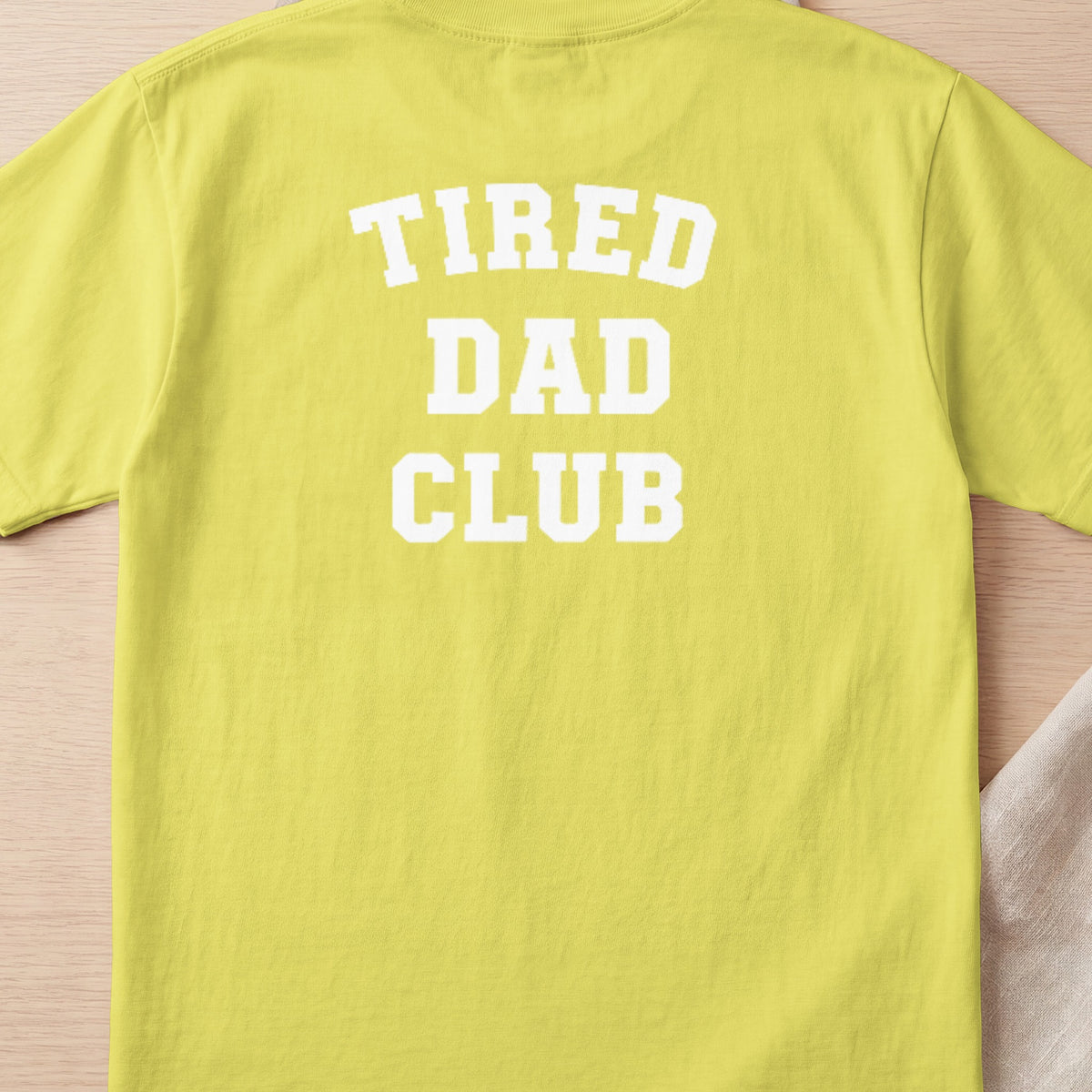 Yellow t-shirt with white text "TIRED DAD CLUB" on the back.
