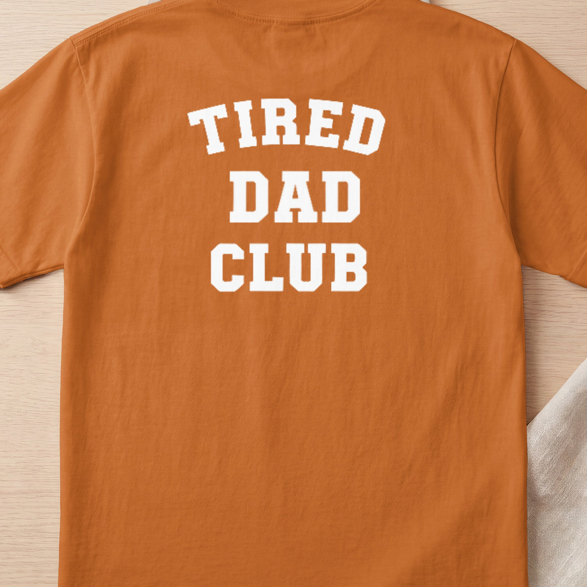 Orange t-shirt with white text reading "TIRED DAD CLUB".