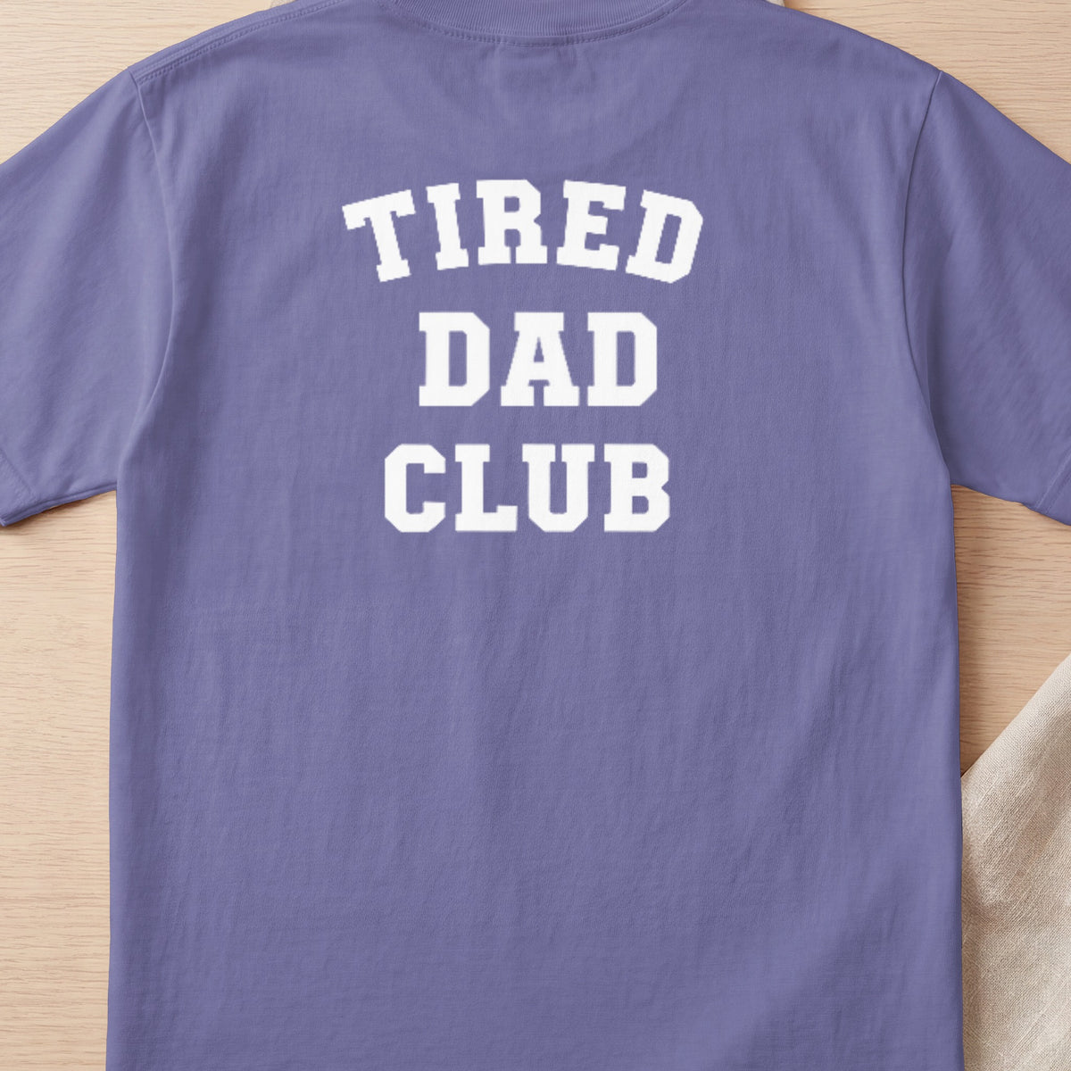 Purple t-shirt with white text "TIRED DAD CLUB" across the back.