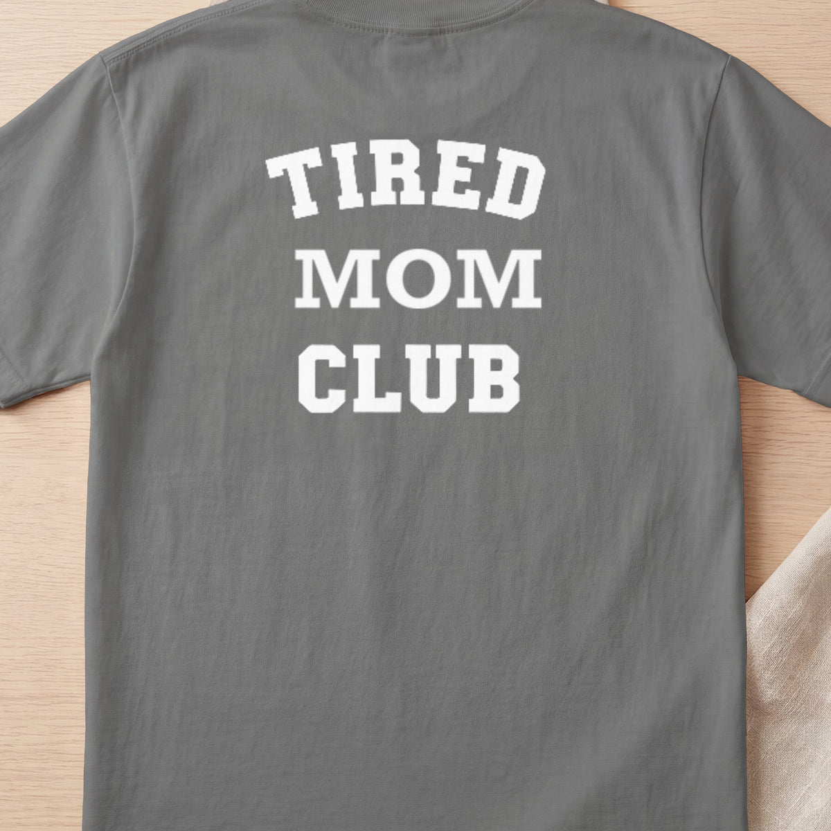 Grey t-shirt with white text reading "TIRED MOM CLUB".
