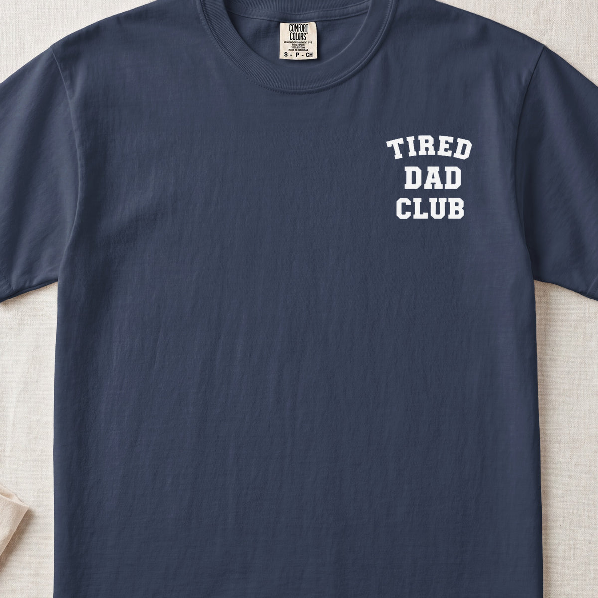 Navy t-shirt with white text "TIRED DAD CLUB" on the chest.