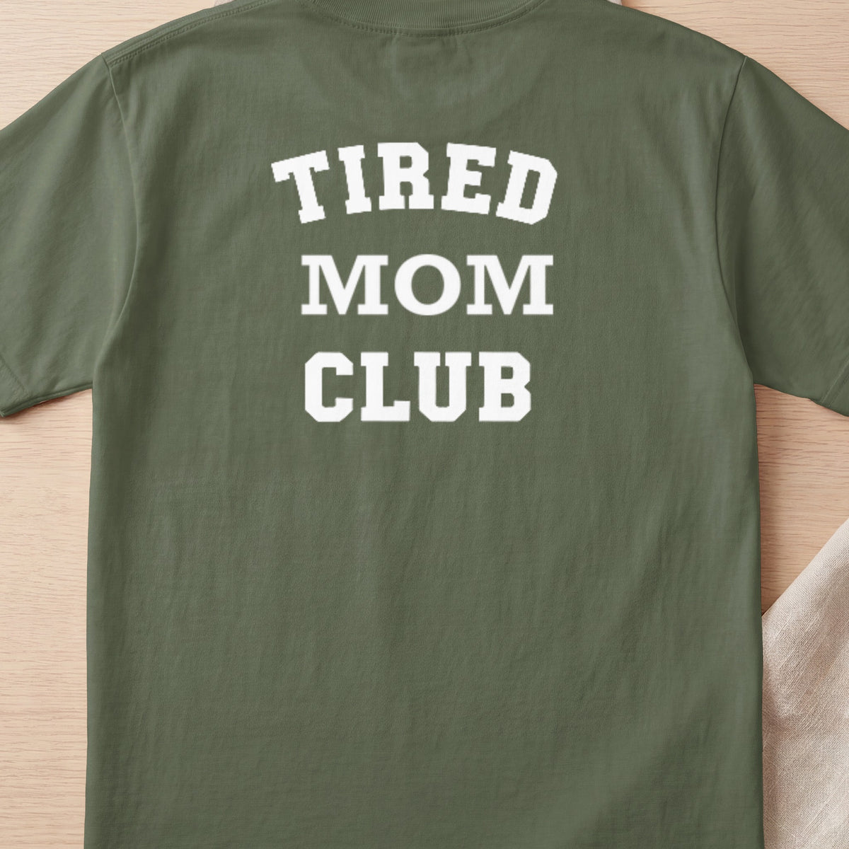 Green t-shirt with white text "TIRED MOM CLUB" on back.