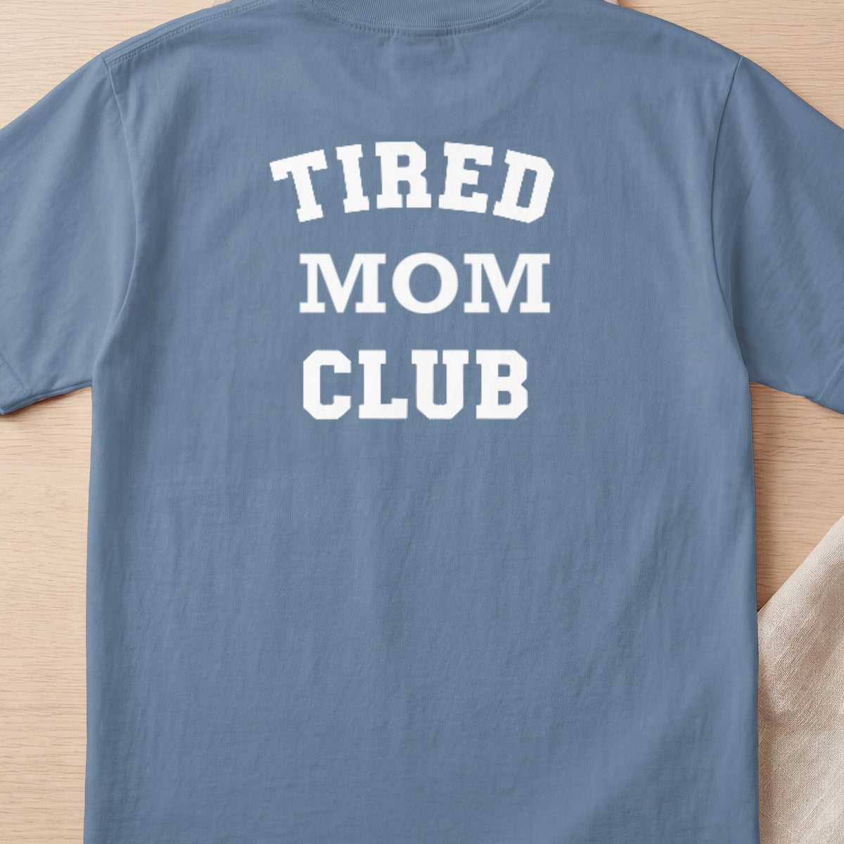 Blue t-shirt with white text reading "TIRED MOM CLUB".